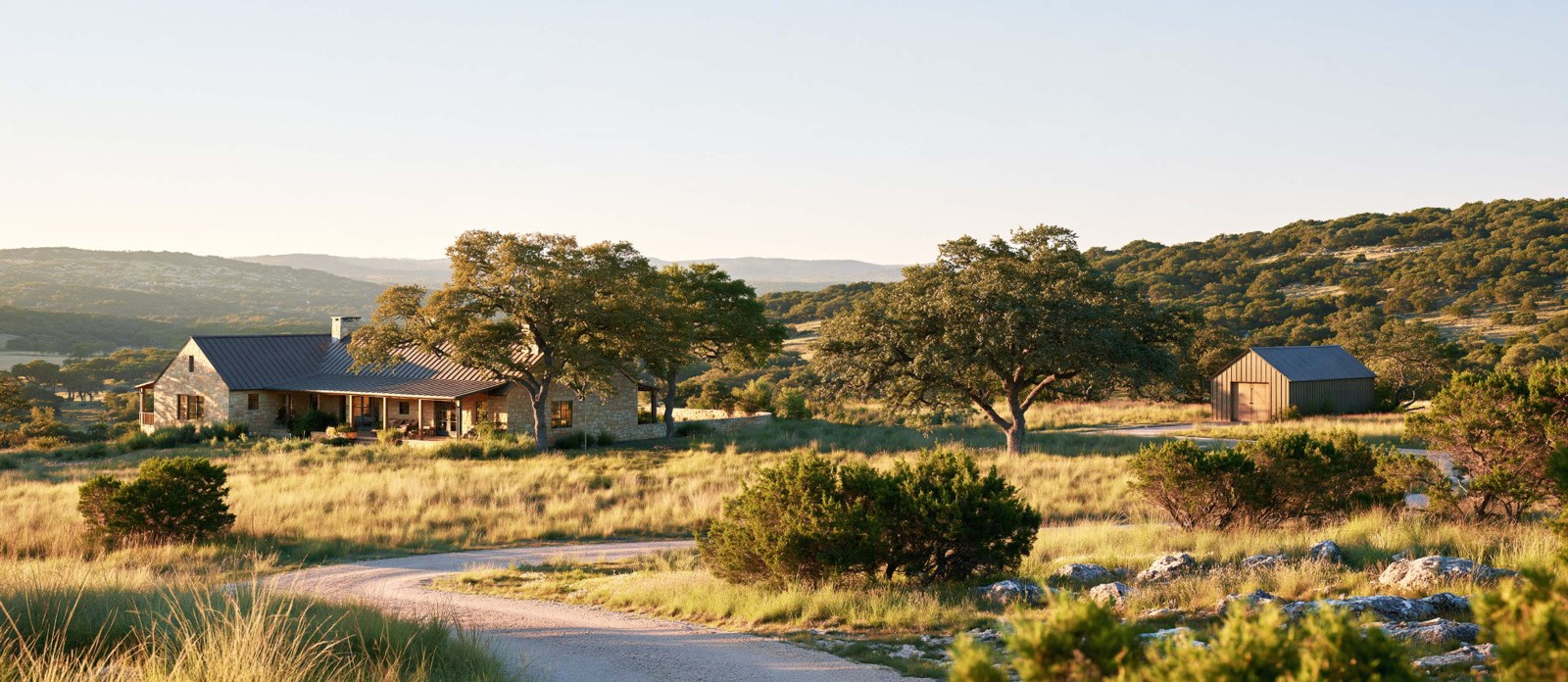 Illustrative Hill Country acreage with a ranch house, detached outbuilding and gravel drive.